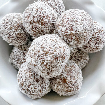 coconut date balls with shredded coconut in bowl.