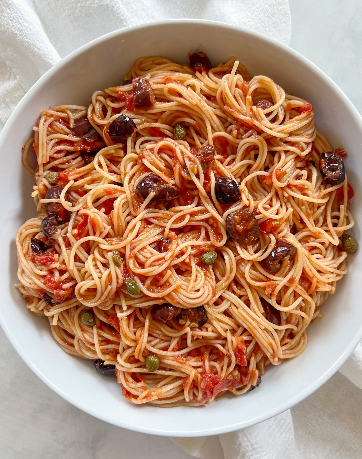 vegan pasta puttanesca in white bowl.