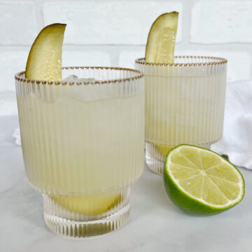 pickle juice margarita with pickle spar and lime.