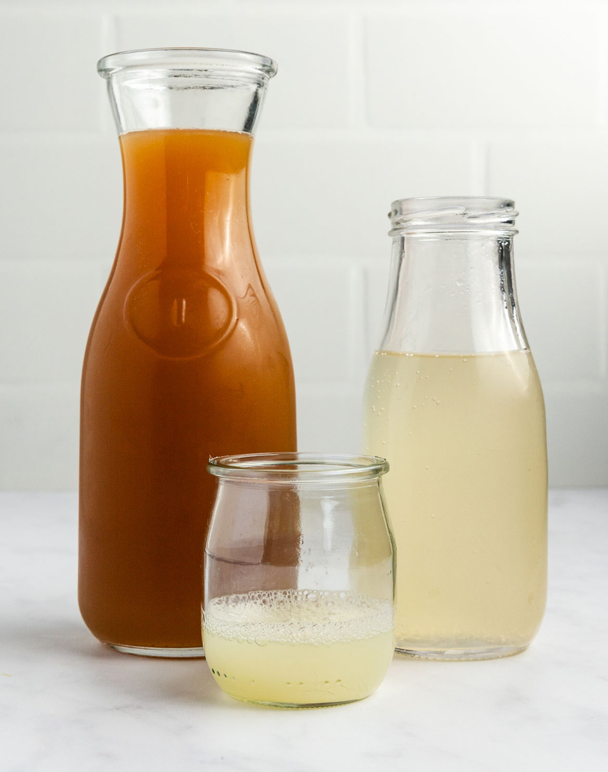 Apple cider, fresh lime juice, and ginger beer shown in glass bottles and jar