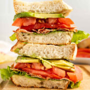 Stacked BLTA halves showing bacon, lettuce, tomato, and avocado