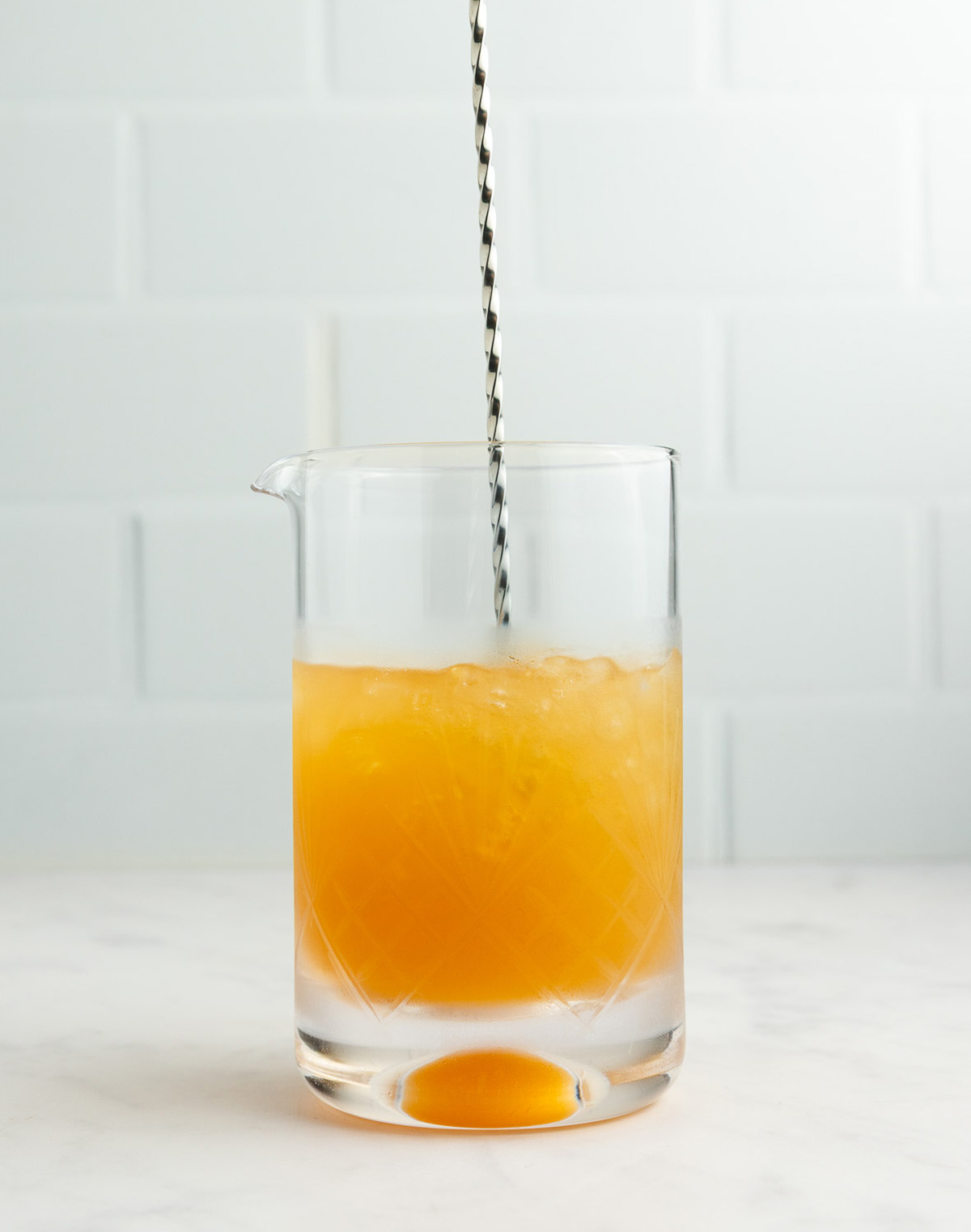 Stirring apple cider mocktail in mixing glass