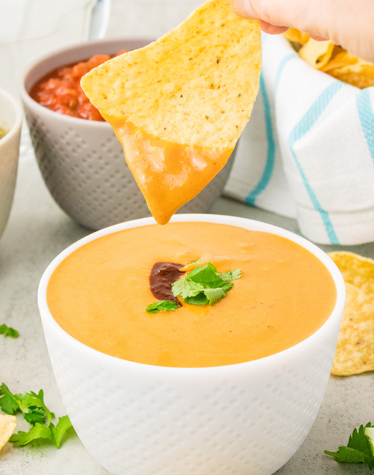 spicy vegan nut free queso cheese sauce with tortilla chip dipping